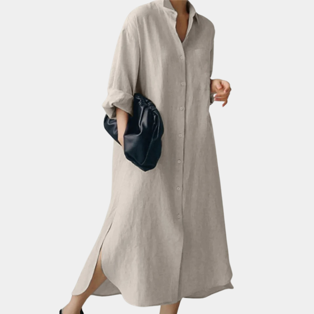 Lichtgrijze oversized damesjurk met lange mouwen en knoopsluiting, gecombineerd met een zwarte handtas. Stijlvolle casual mode voor dames.