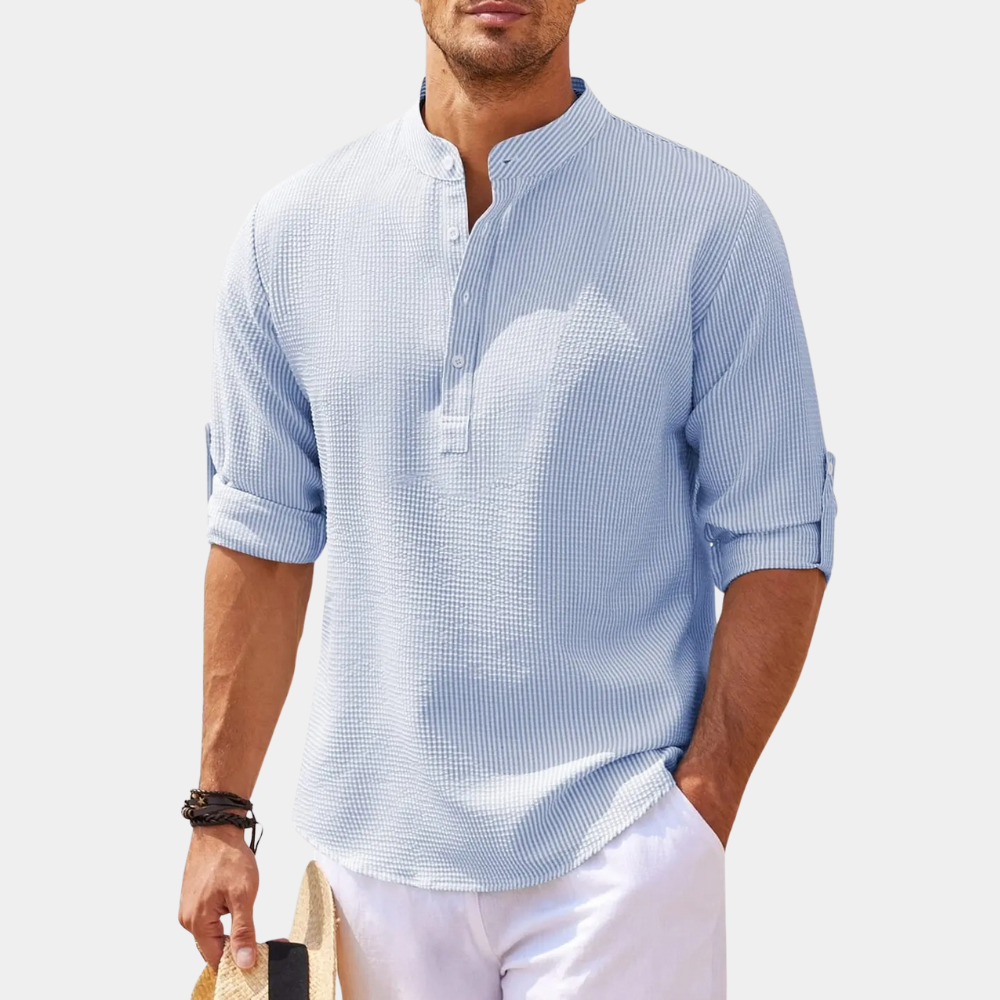 Lichtblauw herenoverhemd met opgerolde mouwen, mandarin kraag en knoopsluiting. Casual zomerlook, ideaal voor strand of vakantie.