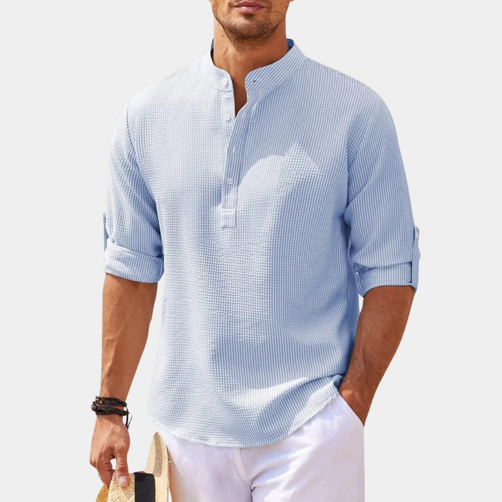 Lichtblauw herenoverhemd met opgerolde mouwen, mandarin kraag en knoopsluiting. Casual zomerlook, ideaal voor strand of vakantie.