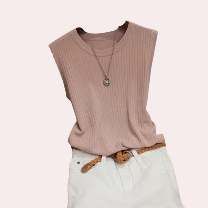 Roze mouwloze ribgebreide top met ronde hals, gecombineerd met witte broek en gevlochten riem. Modieuze dameskleding, casual zomeroutfit.