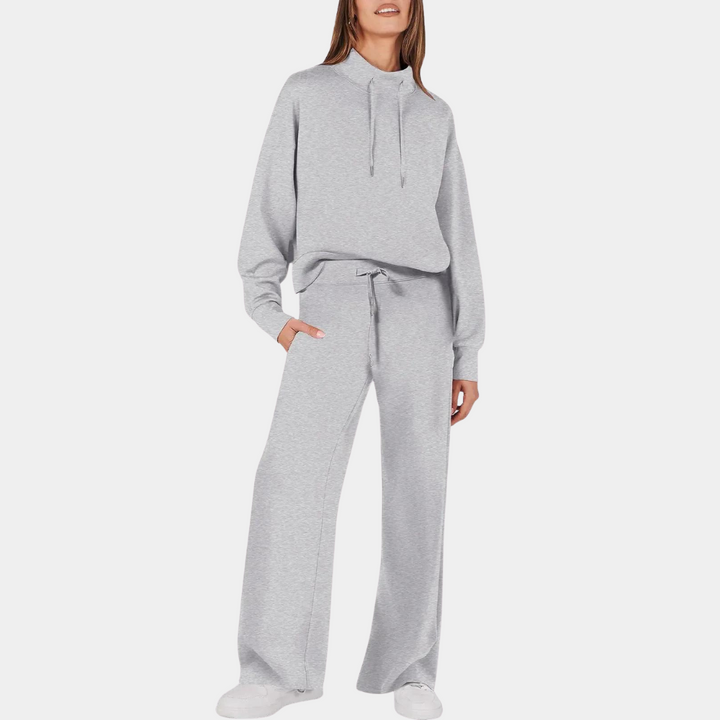 Grijze dames trainingspak met capuchon en wijde broek, comfortabele loungewear, casual mode, perfect voor thuis of sportieve activiteiten.