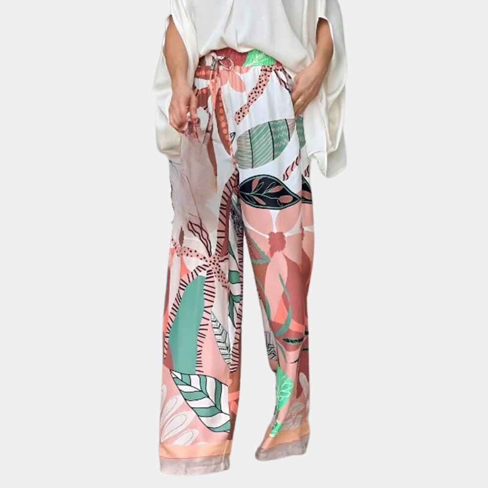 Witte blouse en kleurrijke, wijde broek met tropisch bladpatroon voor dames. Modieuze zomeroutfit, comfortabele pasvorm, trendy design.