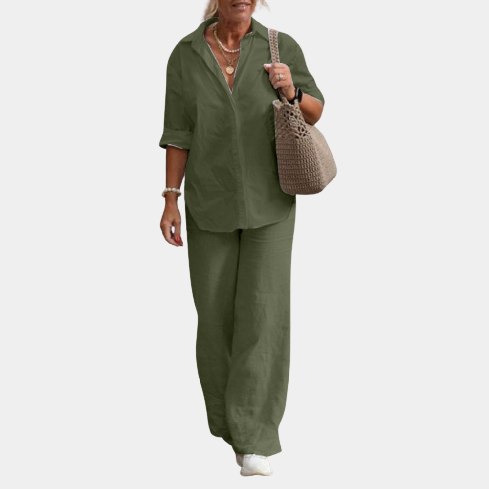 Vrouw in legergroen linnen pak met blouse en wijde broek, draagt een beige gehaakte tas en witte sneakers. Modieuze dameskleding outfit.