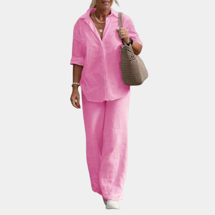 Vrouw in roze linnen outfit met blouse en wijde broek, draagt een bruine geweven tas. Casual zomerlook, modieuze dameskleding.
