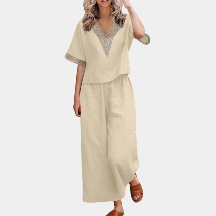 Vrouw in beige linnen zomeroutfit met wijde broek en V-hals top, casual en stijlvol, perfect voor warme dagen. Comfortabele sandalen completeren de look.