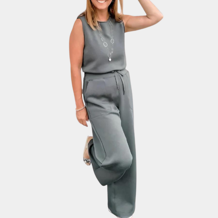 Grijze dames jumpsuit zonder mouwen, elegante pasvorm, met ceintuur en wijde pijpen. Perfect voor casual en zakelijke gelegenheden.