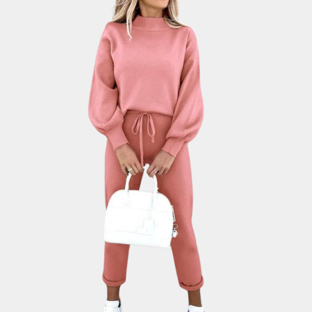 Vrouw in roze trui en broek met witte handtas, modieuze dameskleding, casual outfit, trendy herfstmode, comfortabele stijl.