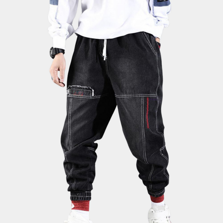 Zwarte baggy jeans voor heren met witte stiksels, elastische tailleband en enkelboorden. Casual streetwear stijl, ideaal voor dagelijks gebruik.