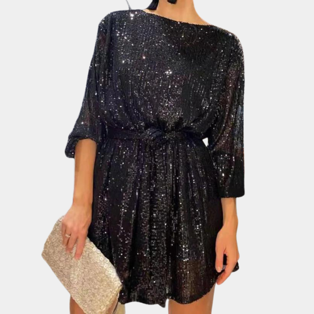 Zwarte paillettenjurk met driekwart mouwen en strikceintuur, gecombineerd met een glinsterende gouden clutch. Perfect voor feestelijke gelegenheden.