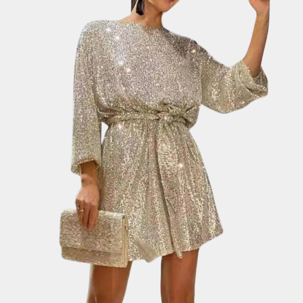 Gouden paillettenjurk met lange mouwen en strikceintuur, gecombineerd met bijpassende clutch. Perfect voor feestelijke gelegenheden.