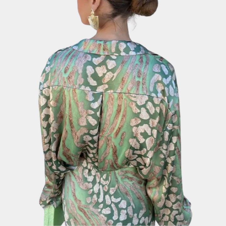 Vrouw in groene zijden blouse met abstract luipaardprint, gouden oorbellen, opgestoken haar. Modieuze dameskleding, luxe uitstraling.