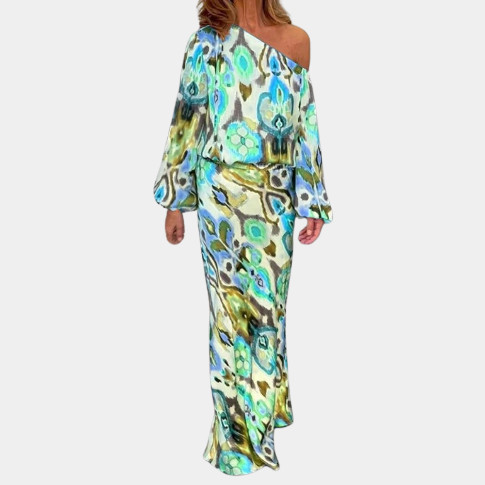 Vrouw in kleurrijke, asymmetrische maxi-jurk met blauwe en groene bloemenprint, lange mouwen, off-shoulder ontwerp. Perfect voor zomer- en strandmode.