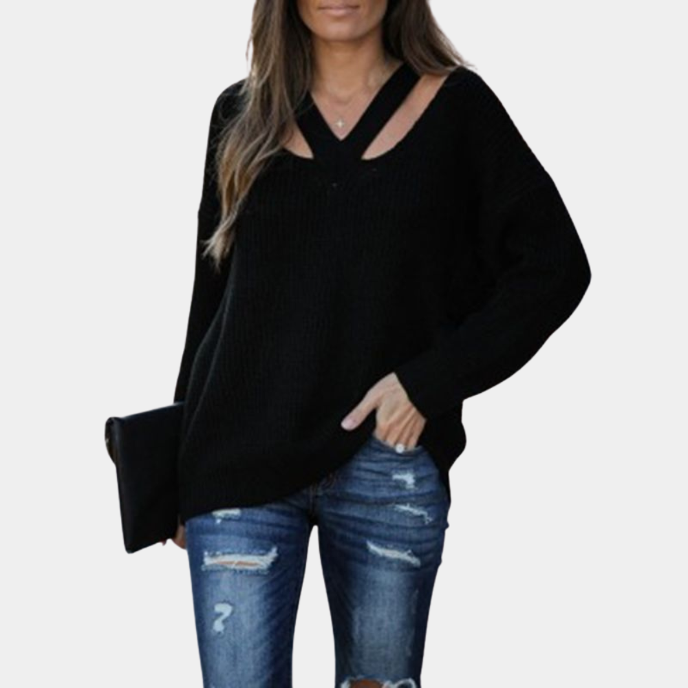 Vrouw in zwarte trui met V-hals en gescheurde blauwe jeans, houdt zwarte clutch. Modieuze dameskleding, casual herfstoutfit.