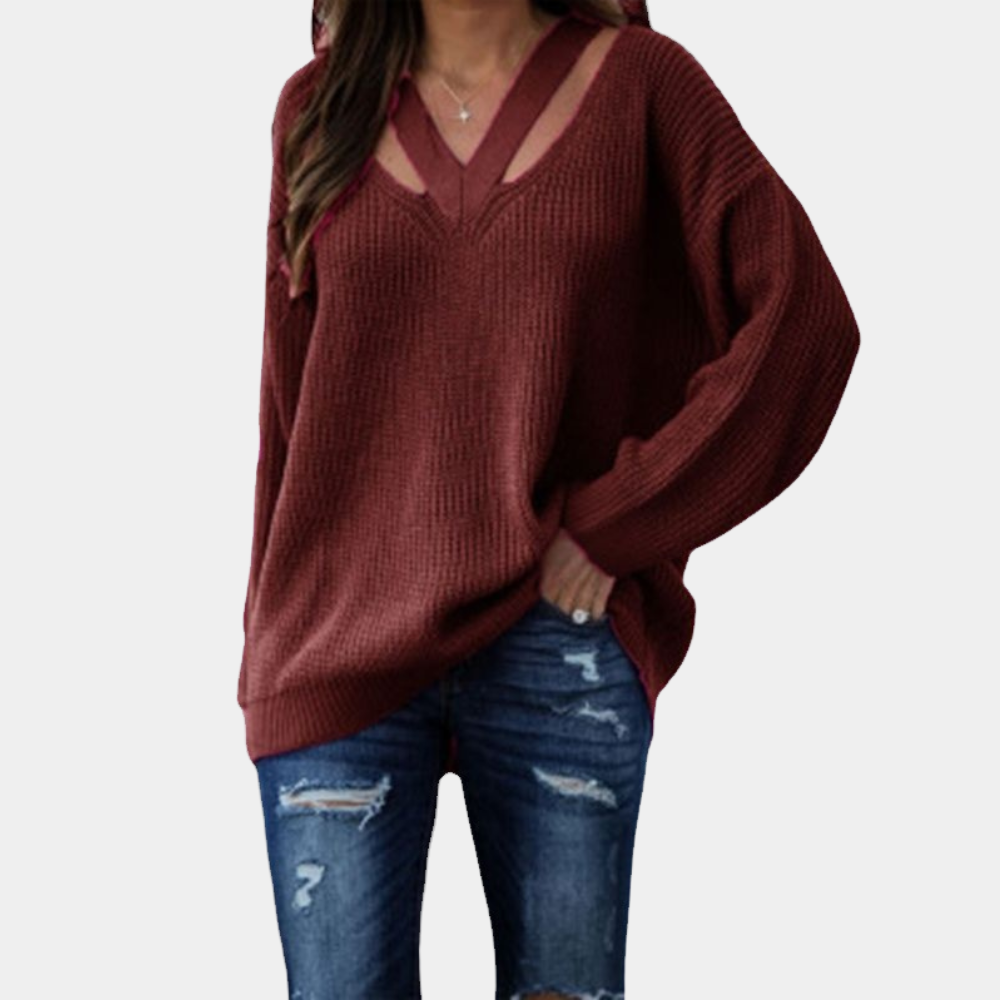 Vrouw in bordeauxrode trui met V-hals en uitgesneden details, gecombineerd met gescheurde jeans. Modieuze dameskleding, herfststijl.