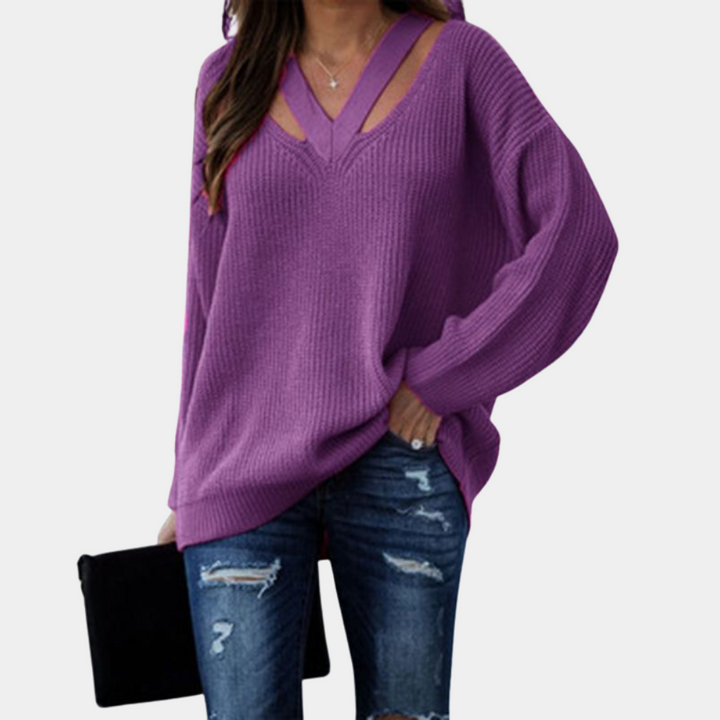 Paarse trui met V-hals en uitgesneden details, gedragen met gescheurde jeans en zwarte clutch. Modieuze dameskleding, casual stijl.