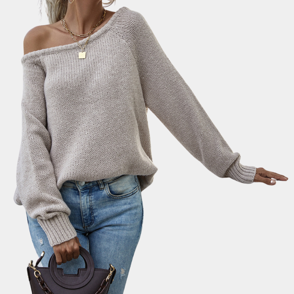 Vrouw in beige off-shoulder trui, casual stijl, met blauwe jeans en zwarte handtas. Modieuze dameskleding, herfstoutfit, comfortabele look.