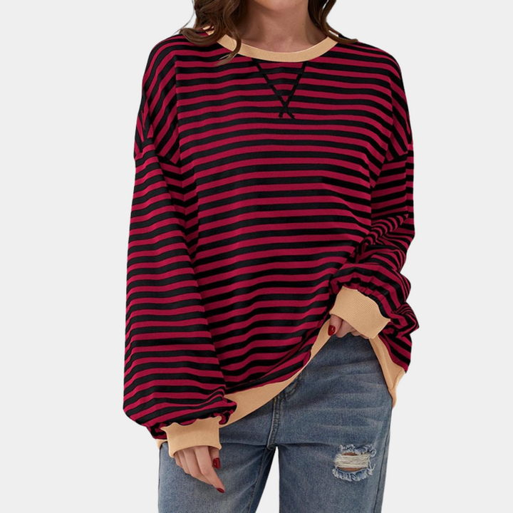 Rood-zwart gestreepte trui met beige boorden, gedragen door model in gescheurde jeans. Modieuze dameskleding, casual stijl.
