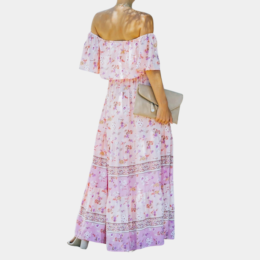 Vrouw in roze bloemenjurk met blote schouders, houdt beige clutch. Zomerse mode, elegante stijl, casual chique outfit.