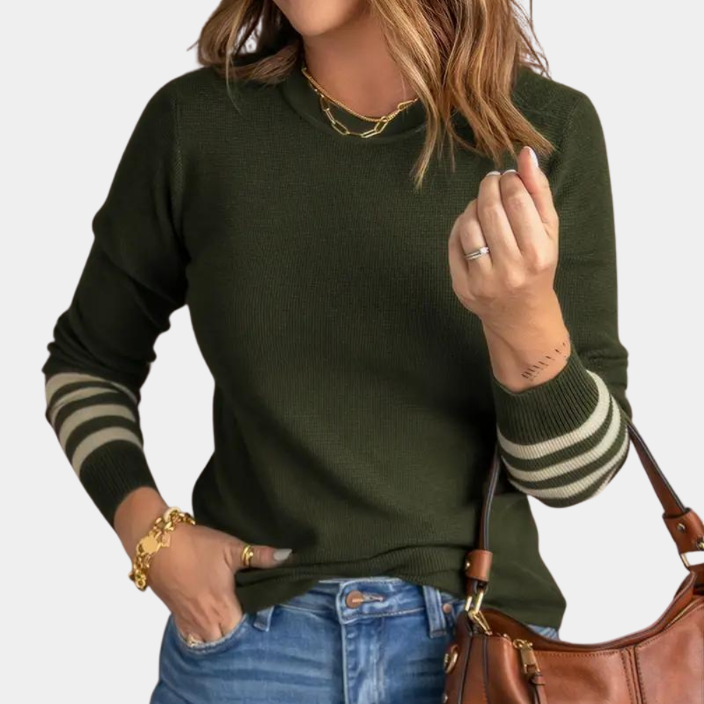 Vrouw in legergroene trui met gestreepte mouwen, gouden sieraden en bruine handtas. Modieuze dameskleding, casual herfstoutfit.