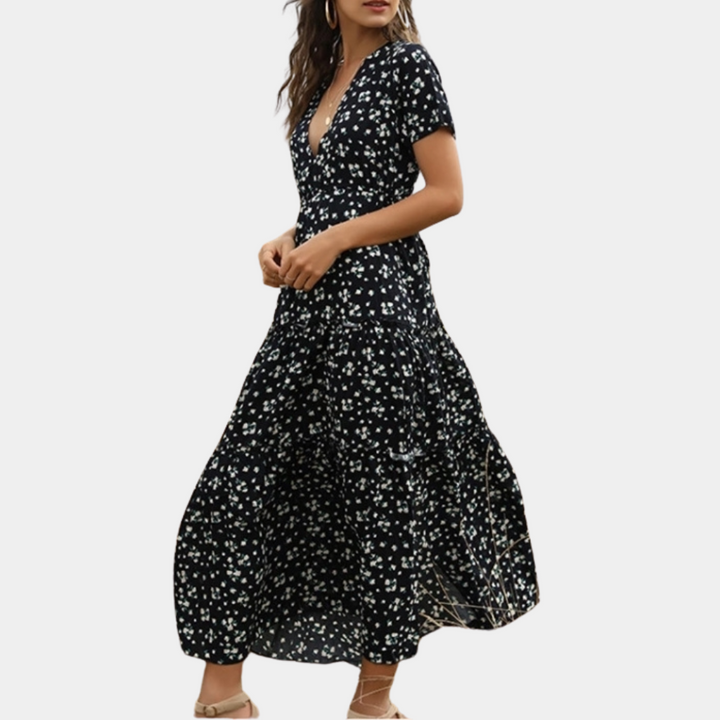 Zwarte maxi-jurk met witte bloemenprint, korte mouwen en V-hals. Perfect voor zomerse gelegenheden. Trendy damesmode, elegante stijl.