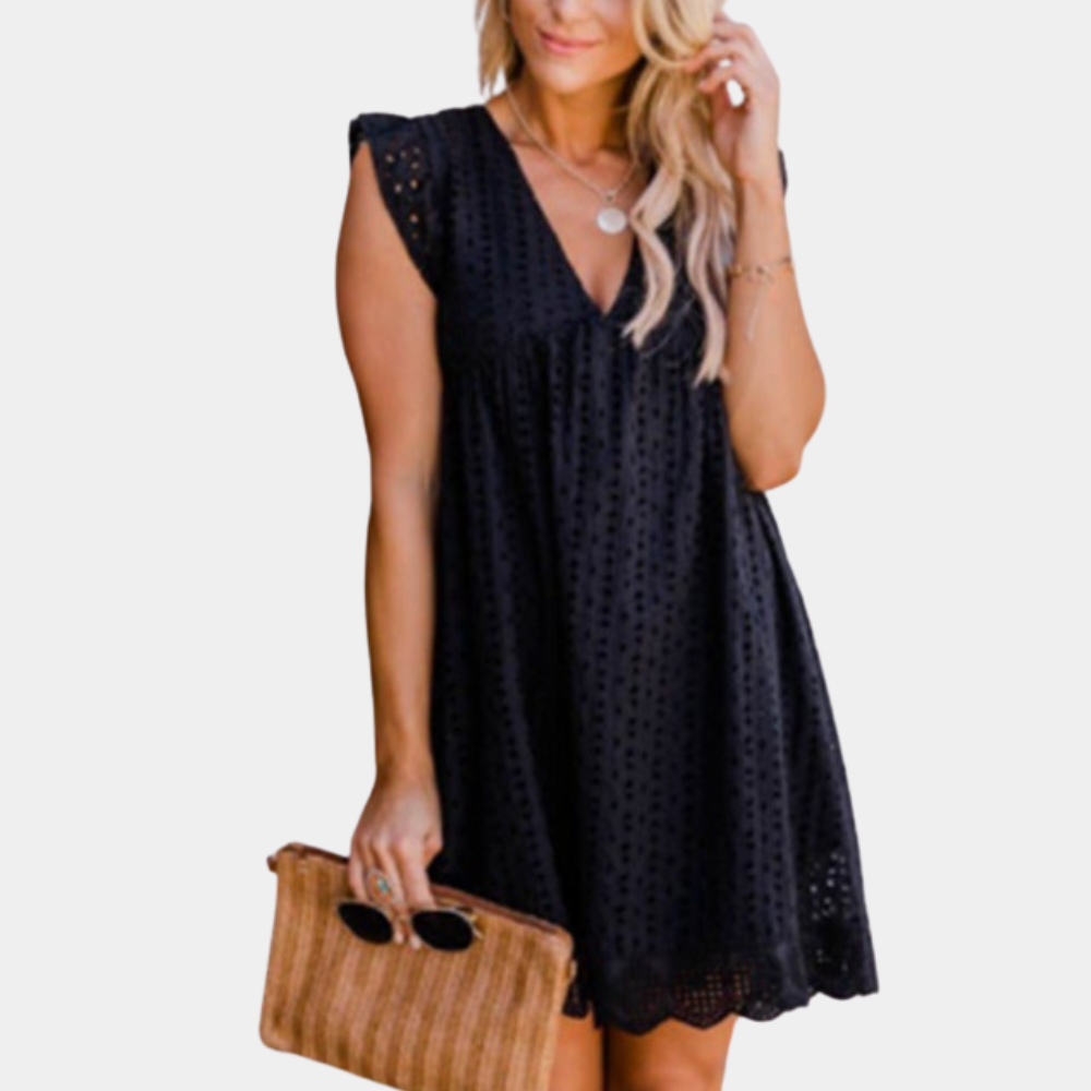 Zwarte kanten zomerjurk met V-hals en korte mouwen, gedragen door vrouw met rieten clutch en zonnebril. Perfect voor casual en elegante gelegenheden.