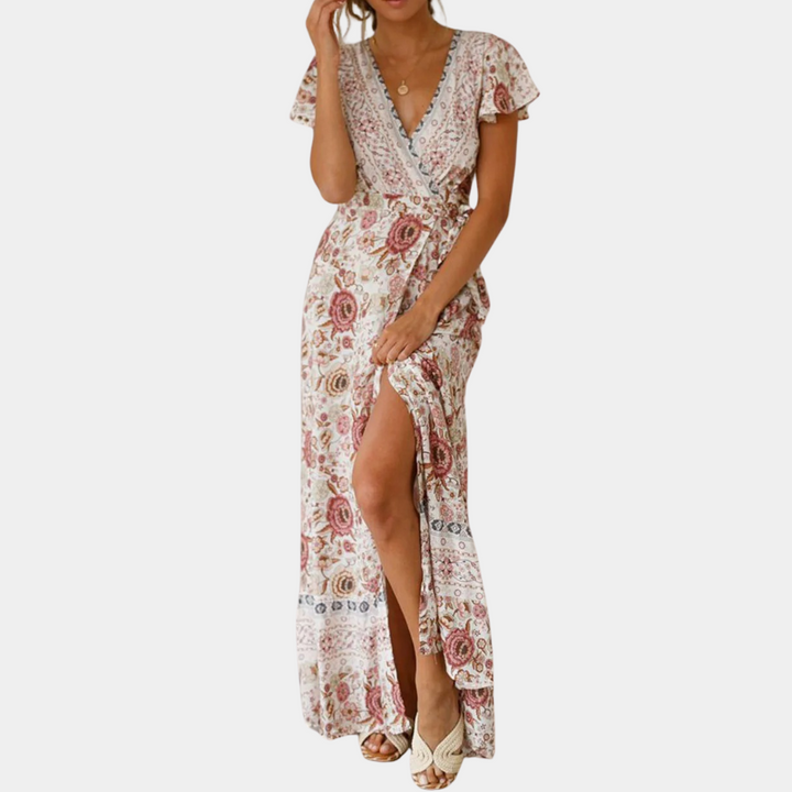 Vrouw in lange, beige bloemenjurk met V-hals en korte mouwen, elegante zomermode, bohemian stijl, perfect voor casual en feestelijke gelegenheden.