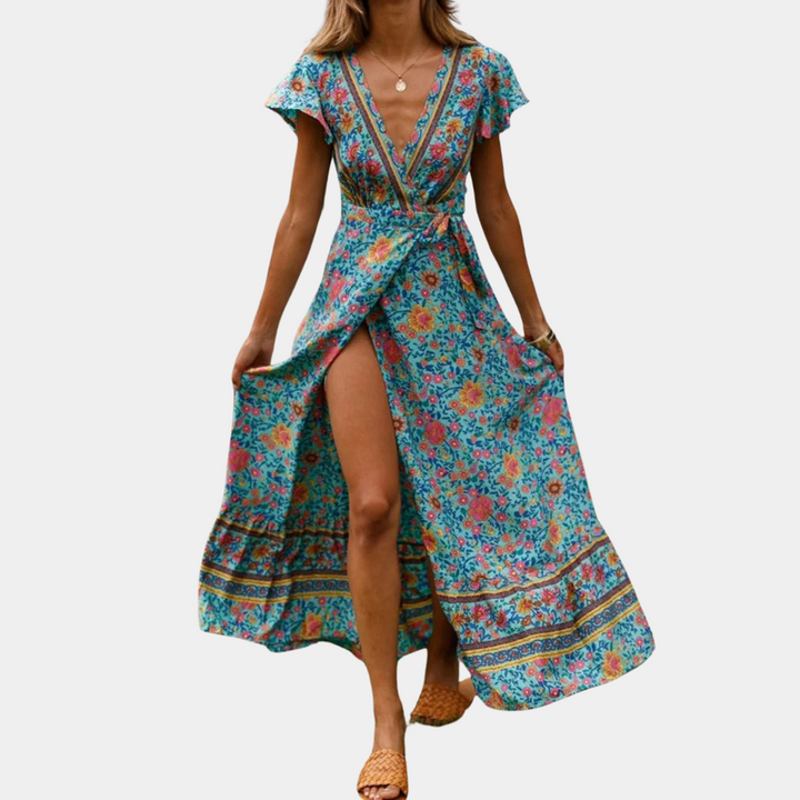 Vrouw in kleurrijke, bloemenprint maxi-jurk met diepe V-hals en split, zomermode, bohemian stijl, groene achtergrond, casual elegantie.