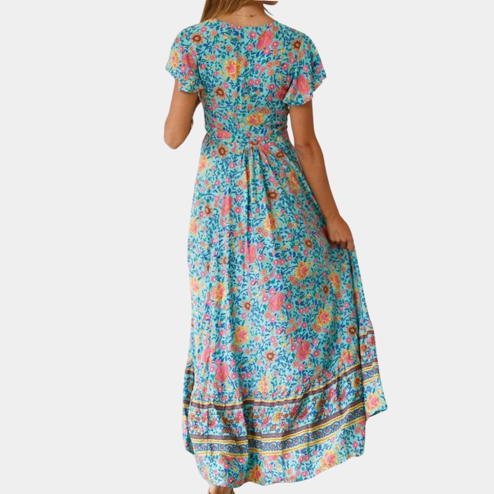 Vrouw in lange, kleurrijke bloemenjurk met korte mouwen en strikdetail, perfect voor zomerse dagen. Bohemian stijl, modetrend 2023.