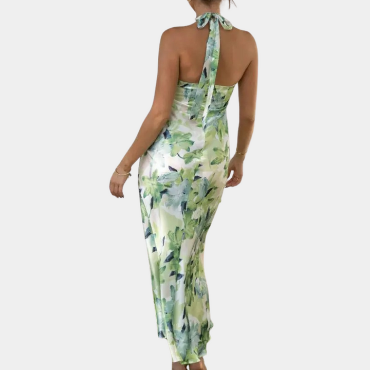 Vrouw in elegante groene bloemenjurk met halternek, rugaanzicht. Perfect voor zomermode, casual en feestelijke gelegenheden. Trendy dameskleding.