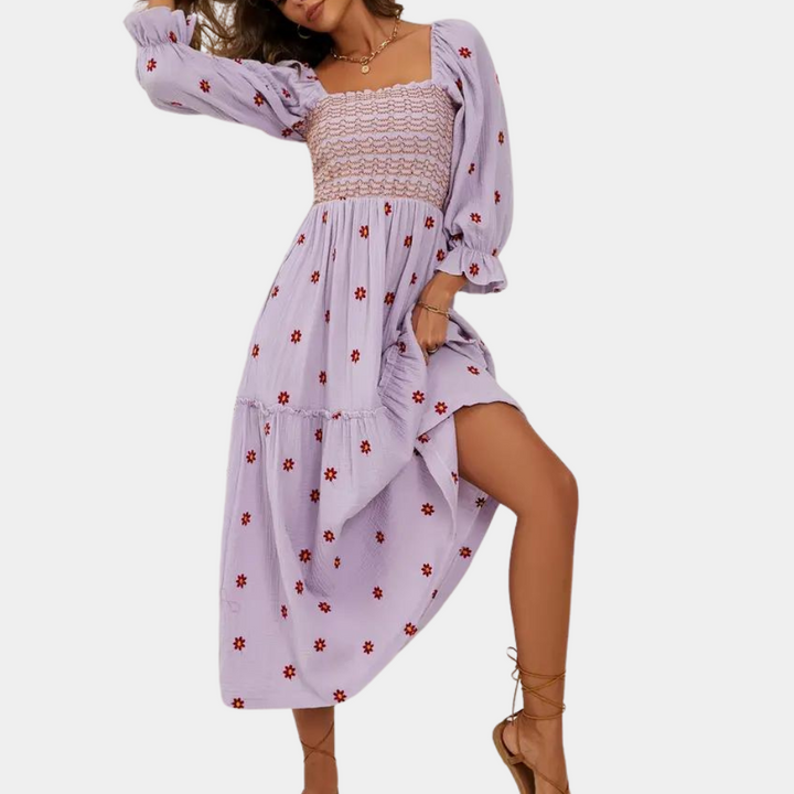 Paarse boho-jurk met bloemenprint, lange mouwen en gesmokte top. Perfect voor zomerse dagen. Trendy damesmode, casual en elegant.