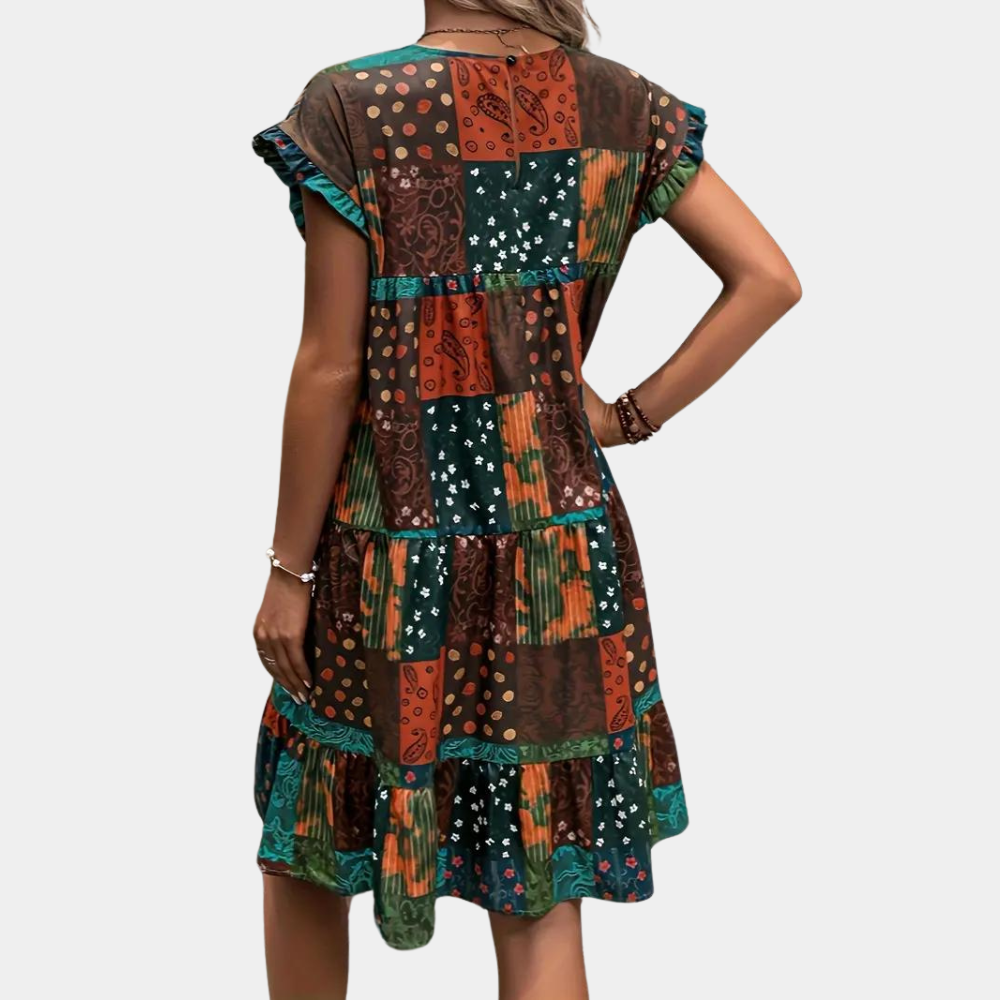 Vrouw in kleurrijke boho jurk met patchwork patroon, korte mouwen en ruches. Ideaal voor zomer, casual stijl, modetrend 2023.