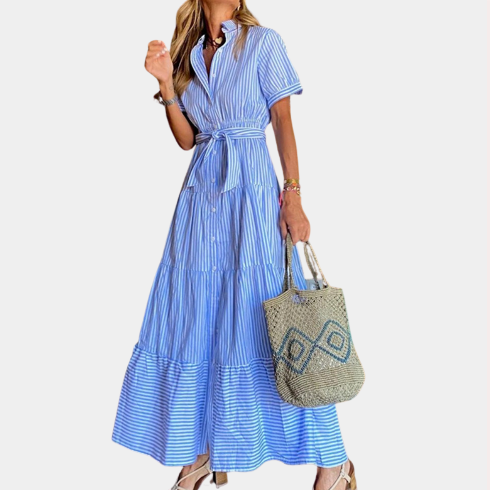 Vrouw in blauwe gestreepte maxi-jurk met ceintuur, draagt een geweven tas. Zomerse mode, casual elegantie, dameskleding.