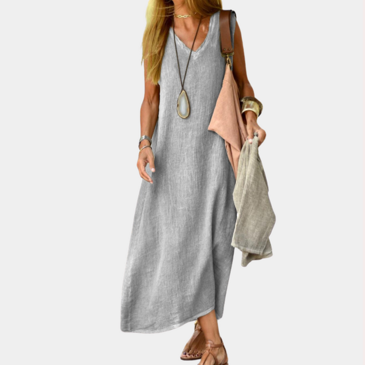 Grijze linnen maxi-jurk voor dames, mouwloos ontwerp, casual zomeroutfit, gecombineerd met sandalen en accessoires, ideaal voor warme dagen.