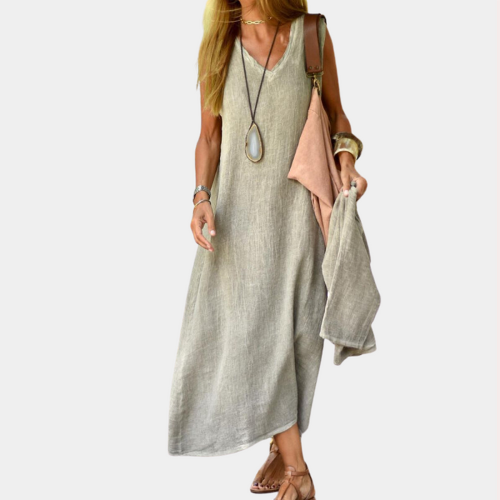 Vrouw in khaki linnen jurk met lange ketting en sandalen, draagt een tas en sjaal. Zomerse mode, casual stijl, comfortabele kleding.