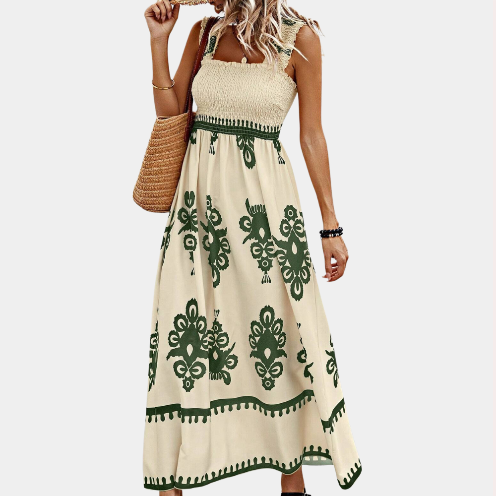 Vrouw in lange, mouwloze jurk met groen patroon, draagt een rieten tas. Zomerse boho-stijl, perfect voor casual en stranduitjes.