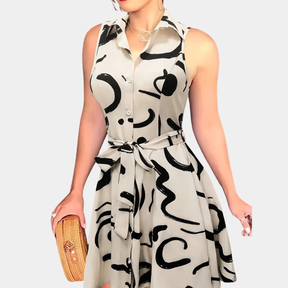 Vrouw in mouwloze witte jurk met zwarte abstracte print, strikceintuur en knoopsluiting, houdt een rieten handtas vast. Modieuze zomeroutfit.