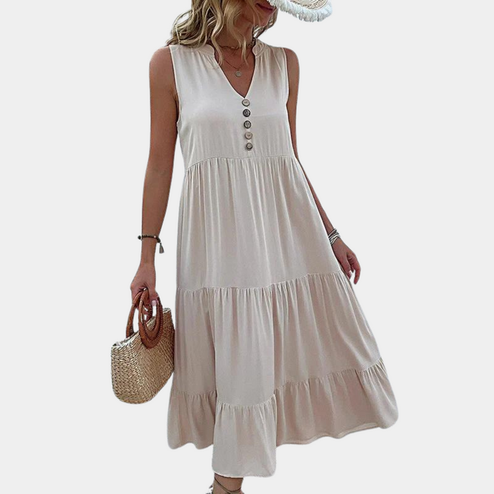 Beige zomerjurk met knopen, mouwloos en vloeiend ontwerp. Perfect voor casual en stranduitjes. Vrouw draagt strohoed en handtas.