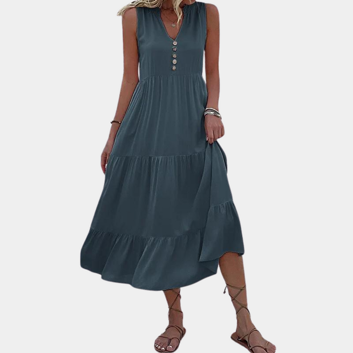 Vrouw in blauwe maxi-jurk met knopen, mouwloos ontwerp, zomermode, casual strandkleding, sandalen, elegante dameskleding.