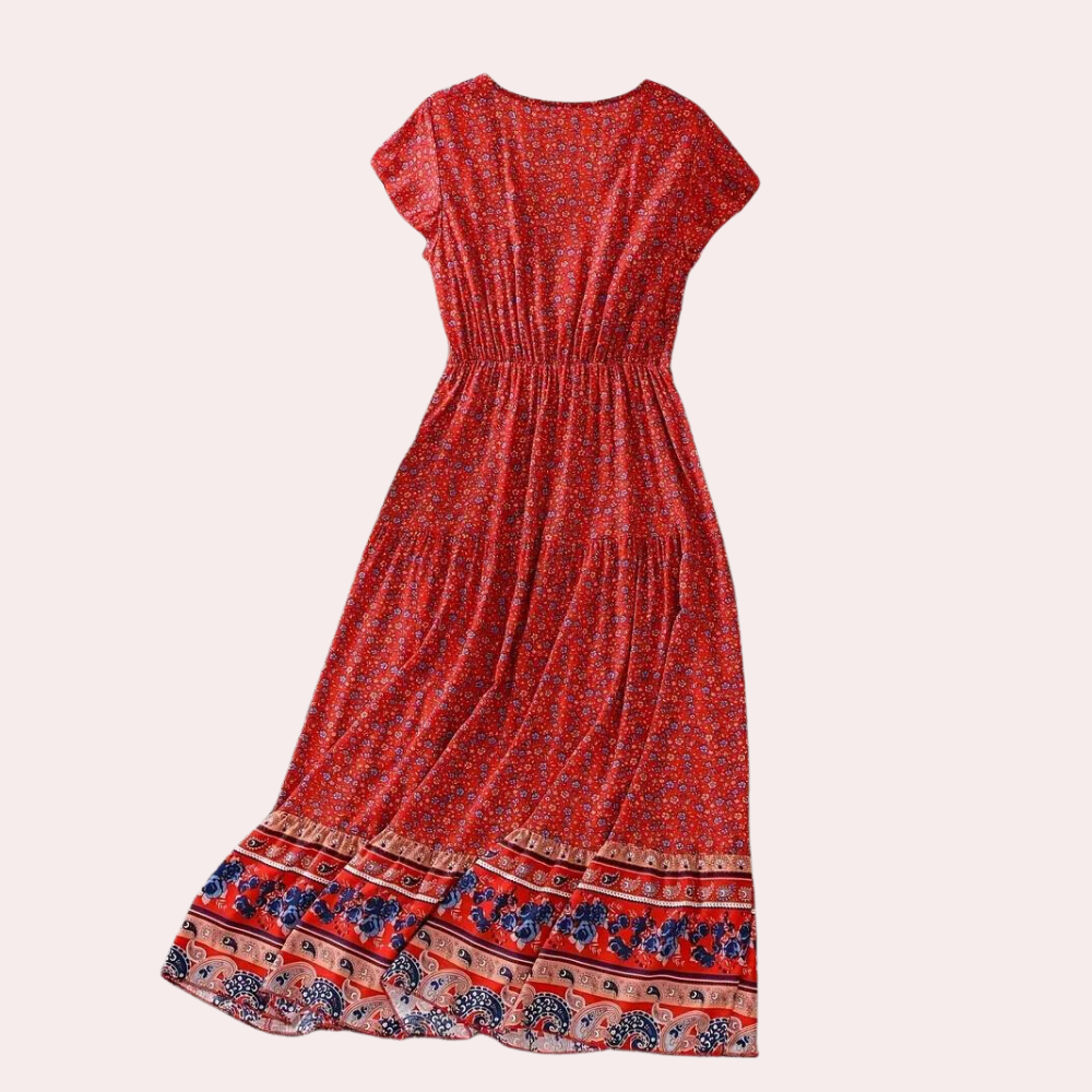 Rode bohemian maxi-jurk met bloemenprint en elastische taille, korte mouwen, en kleurrijke rand. Perfect voor zomerse dagen en festivals.