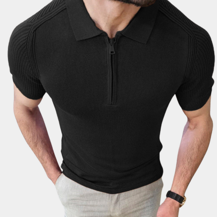Zwarte herenpolo met korte mouwen en ritssluiting, gedragen door een man. Moderne herenkleding, stijlvolle casual outfit.