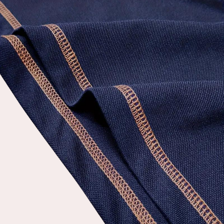 Donkerblauwe stof met beige stiksels, close-up. Hoogwaardige textiel, geschikt voor kleding en interieur. Duurzaam en stijlvol design.