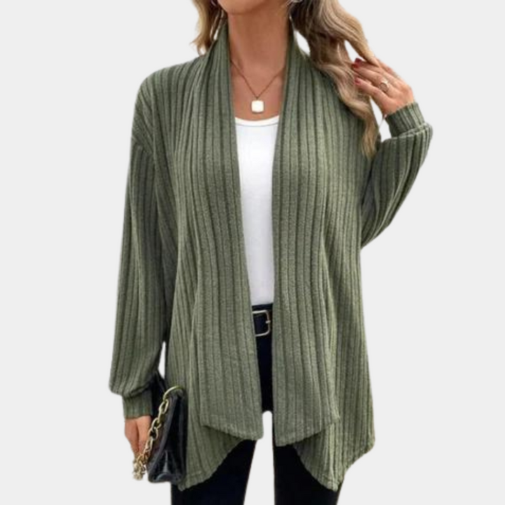 Vrouw draagt een stijlvolle, geribbelde, legergroene cardigan over een witte top, gecombineerd met een zwarte broek en tas. Perfect voor casual mode.