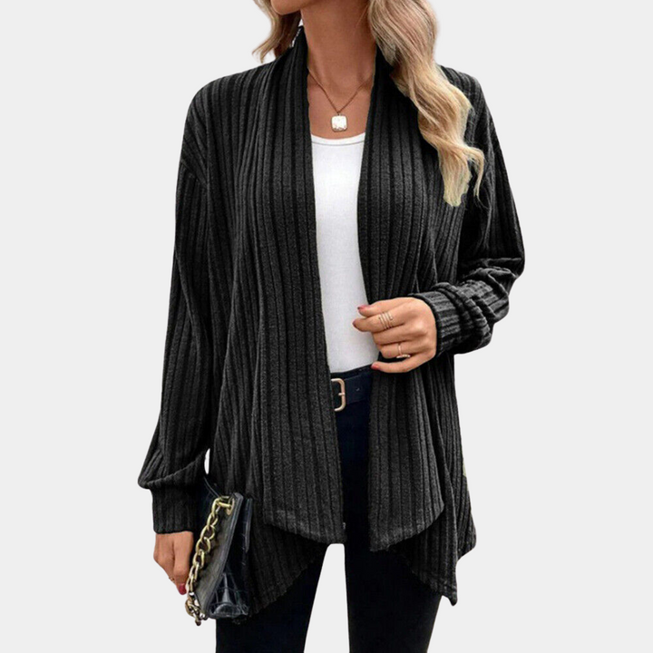 Zwarte geribbelde damesvest, open voorkant, lange mouwen, casual stijl. Perfect voor herfstmode. Accessoire: zwarte tas met ketting.