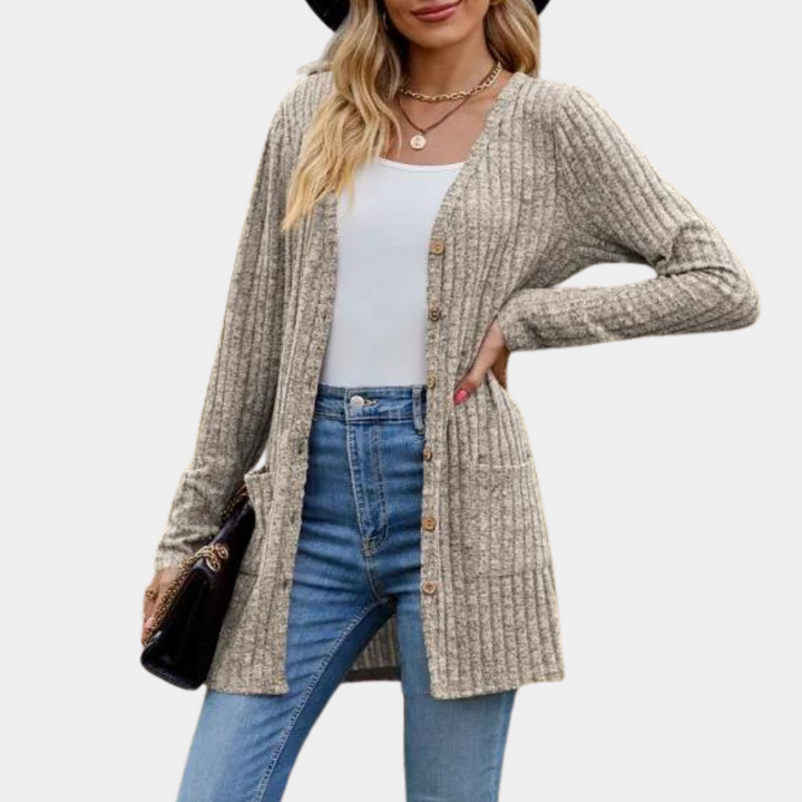 Vrouw draagt lange, geribbelde khaki cardigan met knopen, gecombineerd met blauwe jeans en witte top. Modieuze dameskleding, herfststijl.