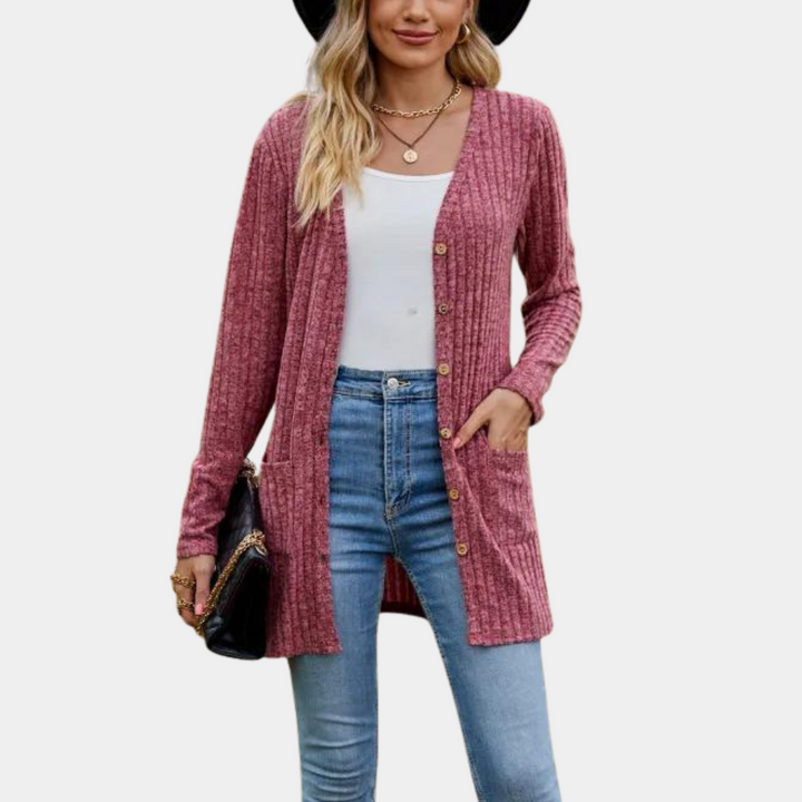 Vrouw in wijnrode gebreide cardigan, witte top en blauwe jeans, met zwarte hoed en tas. Modieuze dameskleding, herfststijl.