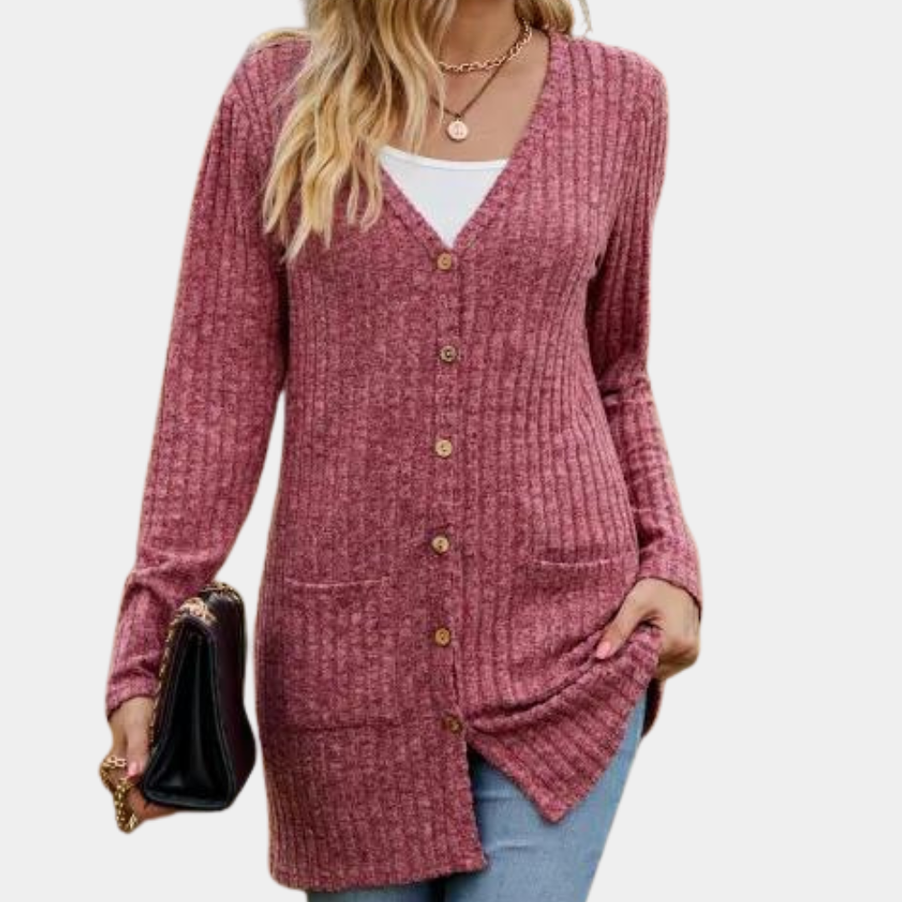 Vrouw draagt een wijnrode, geribbelde cardigan met knopen en zakken, gecombineerd met een witte top en blauwe jeans. Stijlvolle damesmode.