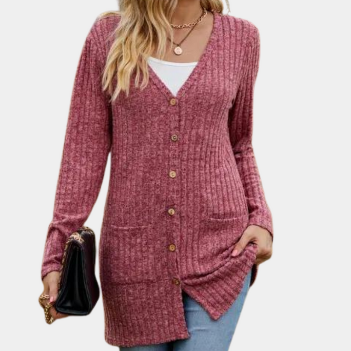 Vrouw draagt een wijnrode, geribbelde cardigan met knopen en zakken, gecombineerd met een witte top en blauwe jeans. Stijlvolle damesmode.