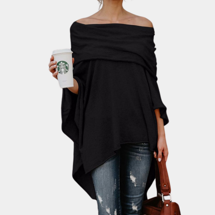 Vrouw in zwarte off-shoulder poncho, draagt Starbucks-beker en bruine tas, casual outfit met gescheurde jeans. Modieuze dameskleding.