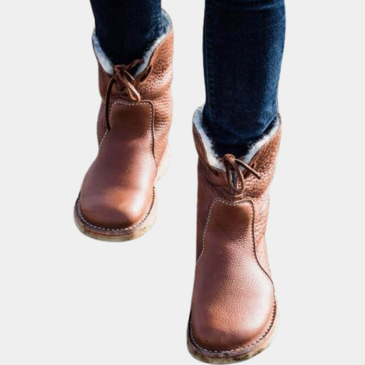 Bruine leren laarzen met schapenvacht voering, gedragen met donkere jeans. Comfortabele winterlaarzen voor dames, stijlvol en warm.
