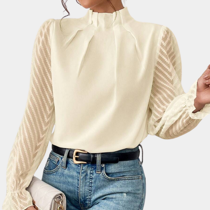 Beige blouse met lange doorschijnende mouwen en zigzagpatroon, gedragen met blauwe jeans en zwarte riem. Elegante damesmode, trendy outfit.